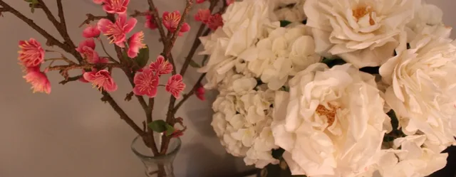 Pink blossom branches beside cream roses