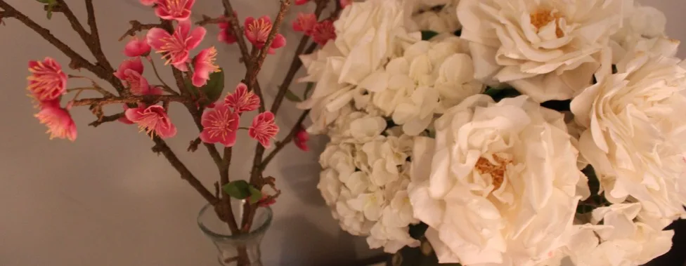 Pink blossom branches beside cream roses