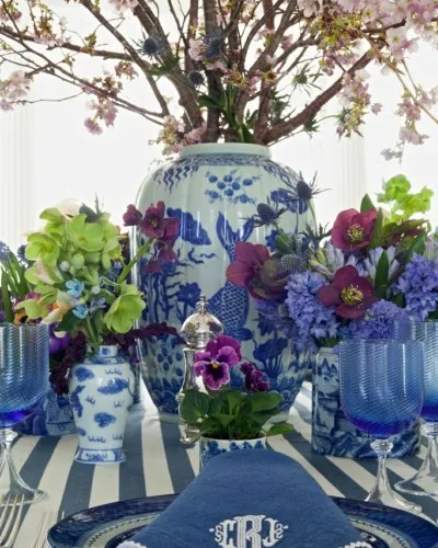 A table setting in blue and white china beneath branches of blossom