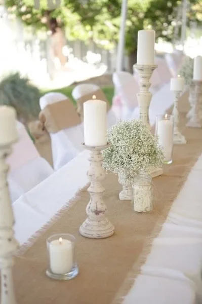 Pillar candles and gypsophila on a hessian table runner