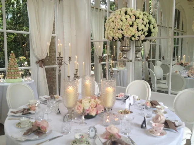 A candlelit round table dressed for a wedding in a conservatory