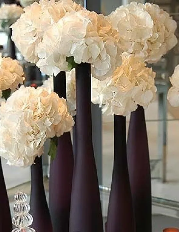 White hydrangeas in tall aubergine glass vases