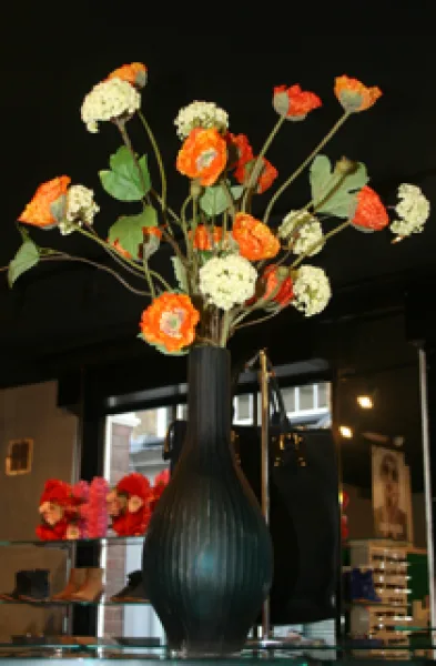 Orange and cream blooms in a tall dark vase