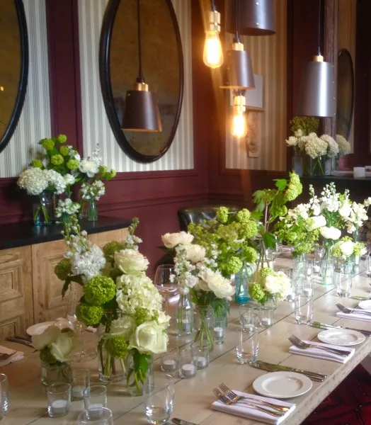 Green and white arrangements along a restaurant table