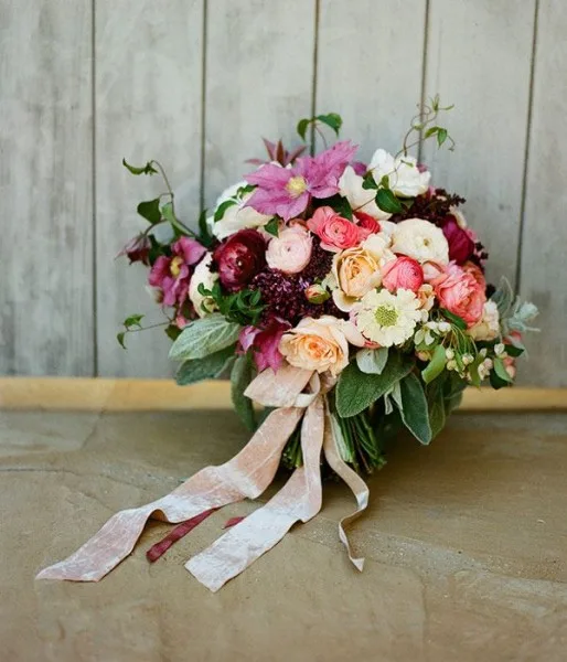 A hand-tied bouquet in pinks and plums with trailing ribbons