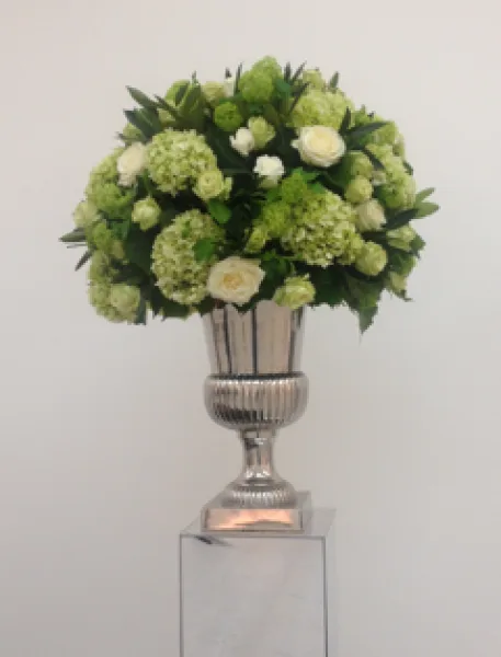 A green and white dome arrangement in a silver urn